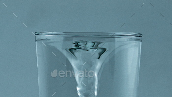 Spinning fresh water vessel closeup. Transparent aqua created funnel glassware