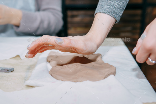 Female hands kneading clay. Production of ceramic products at the master class on ceramics.