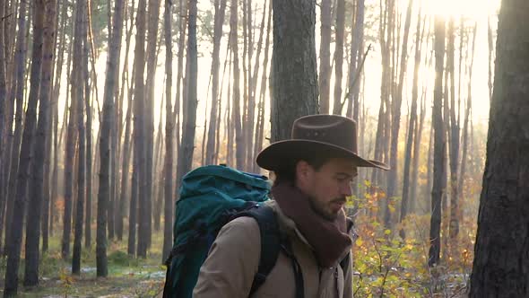 A Man with Camera Walks Along a Trail in the Forest alt
