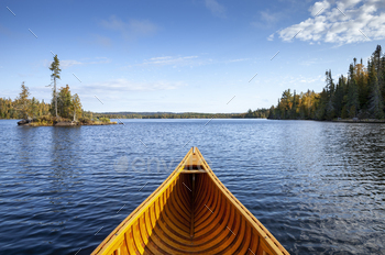 Wooden canoe on a blue Boundary Waters lake with a small island on an autumn morning