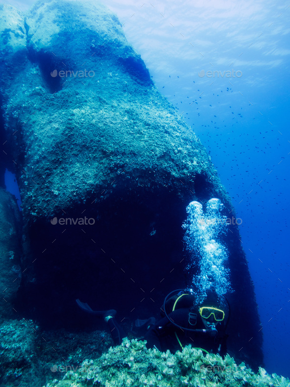 Man diving next to a large rock in Sardinia