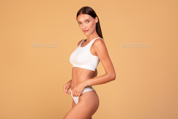 Athletic young lady with perfect figure in underwear posing over beige  background, attractive woman Stock Photo by Prostock-studio
