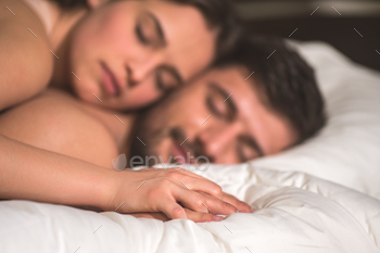 The couple hold hands in the bed