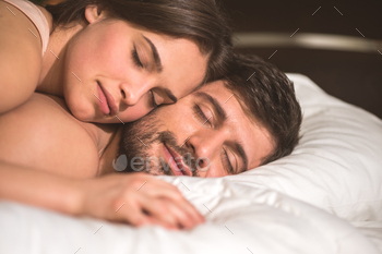 The happy couple hold hands in the bed