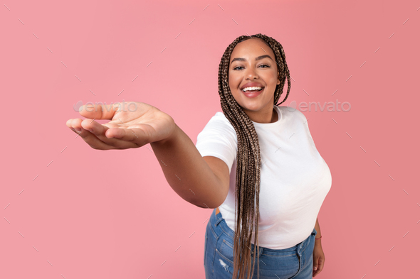 Happy Black Lady Showing Hand Advertising Invisible Product, Pink Background