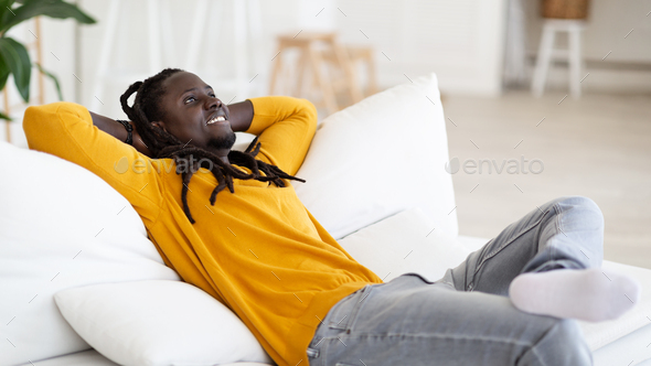 Relaxing Weekend. Happy Smiling Young Black Man Leaning Back On Couch