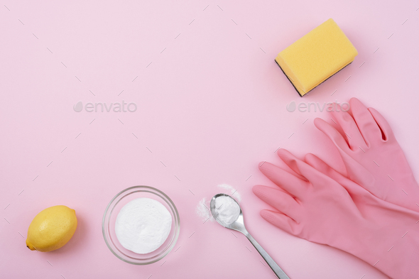 Cleaning gloves, yellow sponge, baking soda and lemon on pink background. Eco cleaning concept. Top