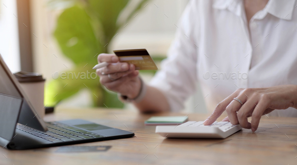 Woman making calculations and shopping online with credit card. Female using calculator, budget and