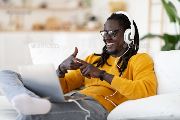 Online Tutoring. Cheerful Black Man In Headphones Making Video Conference On Laptop