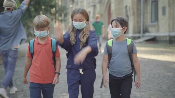 Middle School Pupils Strolling in Sunlight Outdoors with Elder Students Walking at the Background alt