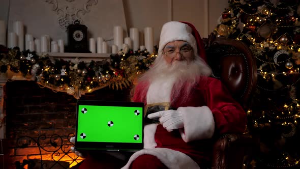 Smiling Santa Claus Points Finger at Laptop Green Screen Christmas Shopping alt