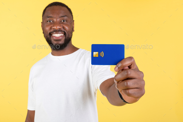 Smiling Black Man Showing Credit Card Advertising Bank, Yellow Background