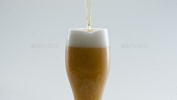 Filling glass golden beer in super slow motion close up. Lager drink pouring.