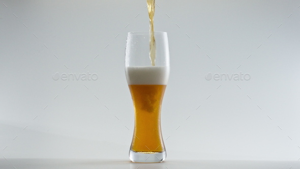 Lager beer filling glass in super slow motion close up. Alcohol drink pouring.