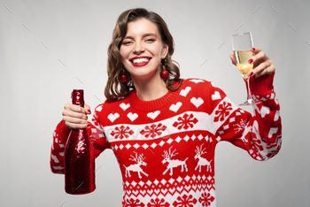 Portrait of woman in reindeer sweater with champagne celebrating winter holidays on gray background