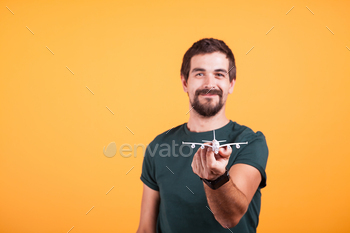 Happy smiling man showing a toy plane to the camera