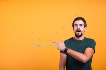 Expressive shocked man pointing at his right with his mouth open