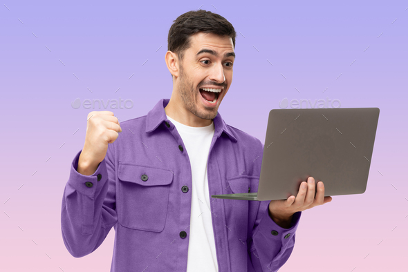 Excited young man in purple shirt looking at laptop screen with WOW expression