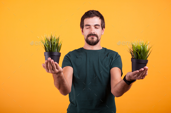 Portrait of positive man in serenity state of mind holds two pots with green grass