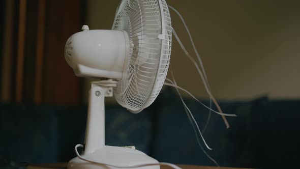 a woman turns on a modern fan, escaping from the summer heat.