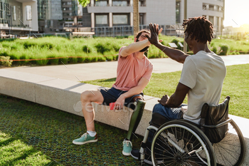 Multiracial people with physical disabilities greeting each other outdoor  