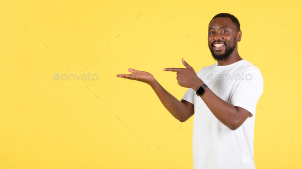 Black Guy Pointing At Hand Holding Invisible Object, Yellow Background - Stock Photo - Images