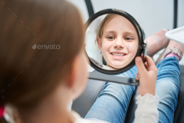 Focused Pre-teen Girl Examining Her Anterior Teeth After Treatment 