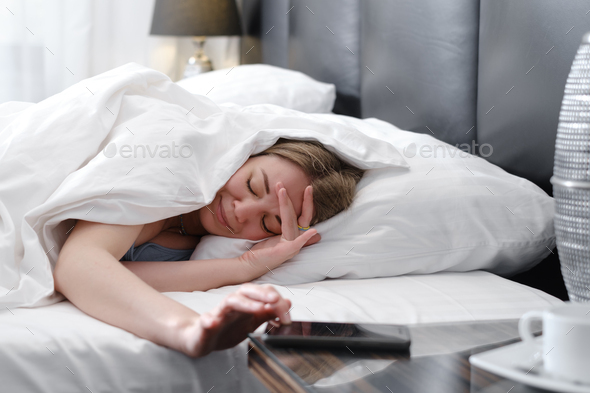 Woman covered with blanket in bed in the morning