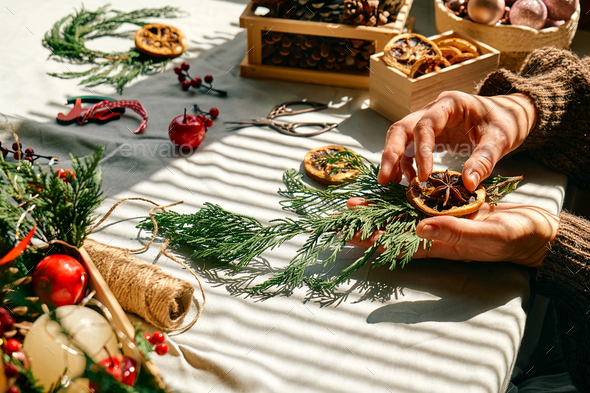 Woman making Christmas arrangement with fir branches and dried oranges. Winter holidays. - Stock Photo - Images