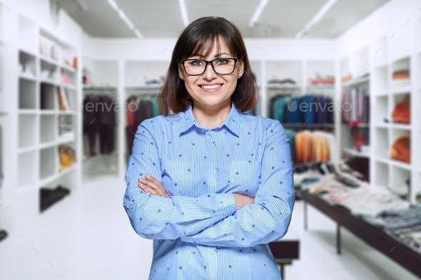 Smiling middle aged woman posing in clothing store Stock Photo by ...