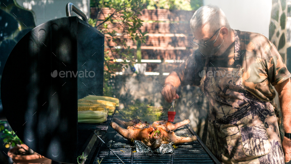 Chef using face mask and cooking whole pig with corn on cob BBQ during covid-19