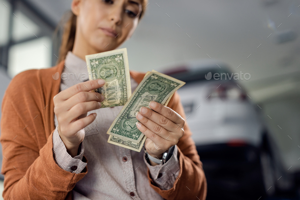Close-up of woman counting money at auto repair shop.