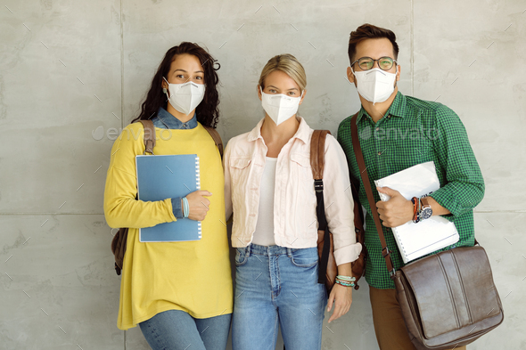Three college friends wearing protective face mask at university hallway.