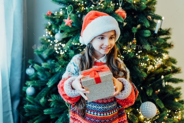 A happy smiling little girl in Santa hat and festive sweater with