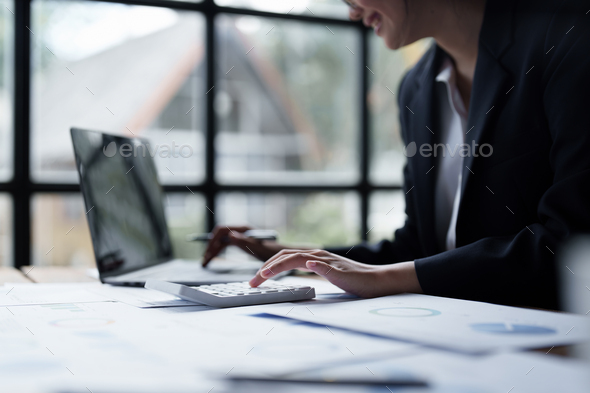 Asian Business Woman or Accountant do math and analyze with calculator and paperwork on desk - Stock Photo - Images
