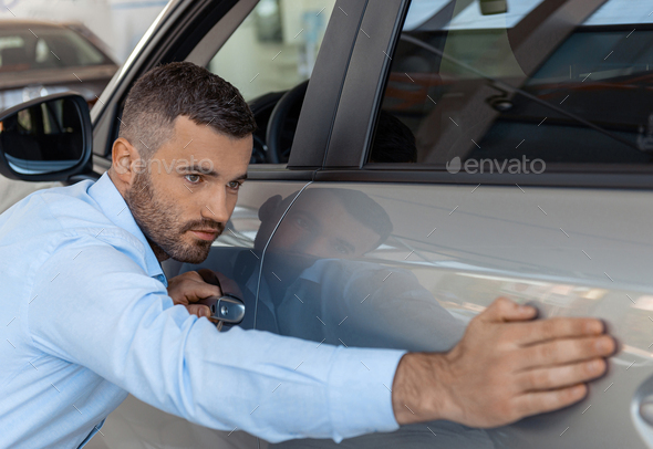 Handsome businessman touching and checking new car. Concept for car rental - Stock Photo - Images