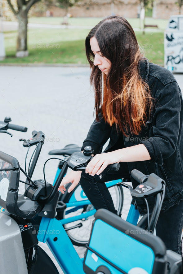 Young woman using phone to unlock and rent an electric bike in the city,new transport sustainable