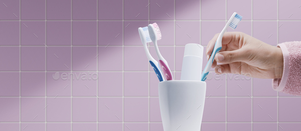 Woman taking her toothbrush in the bathroom - Stock Photo - Images