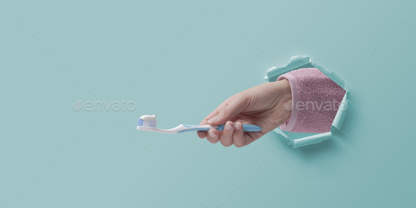 Woman hand in a paper hole holding a tootbrush - Stock Photo - Images