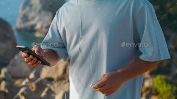 Man hands using smartphone at ocean edge cliff closeup. Athlete guy check phone