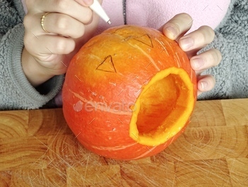 Child is carving pumpkin.