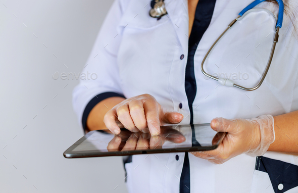 Female physician using digital tablet while standing near desk at clinic emergency hospital.