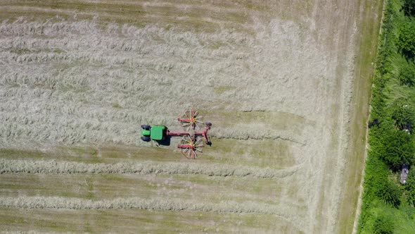 Farmland working - a tractor with its twin rotor rake is cleaning up the field, filmed as top down s alt