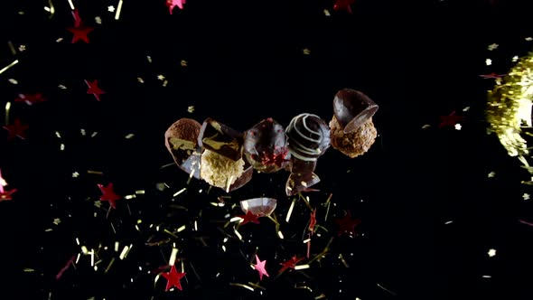 Handmade Luxurious Chocolate Sweets in Burst of Golden Tinsel and Stars Slow Mo