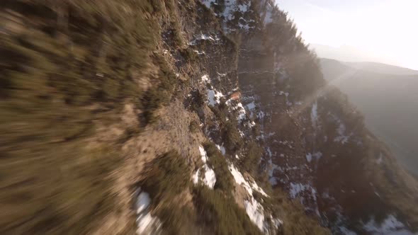 fpv drone diving down an austrian mountain at spring in the evening sun alt