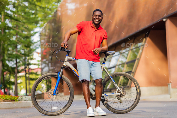 Portrait of handsome smiling stylish hipster with bike in park - Stock Photo - Images