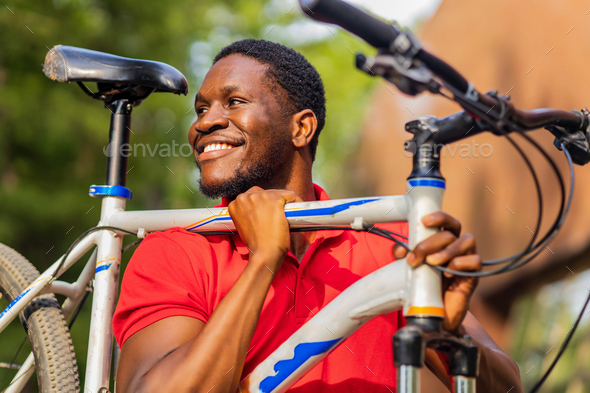 latin amerixan man in casual clothes smiling while leaning on his bike - Stock Photo - Images