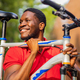 latin amerixan man in casual clothes smiling while leaning on his bike - PhotoDune Item for Sale