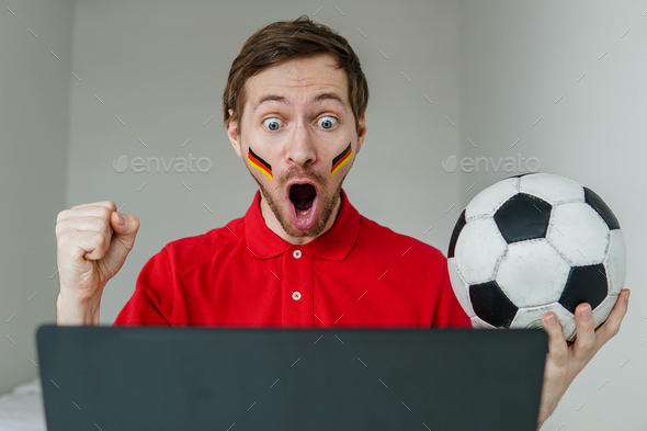 Man support Germany national football team hold in hand soccer ball watch tv live stream on laptop.