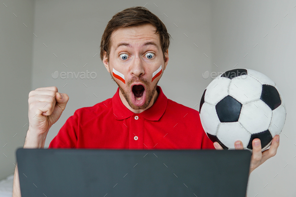 Man support Poland national football team hold in hand soccer ball watch tv live stream on laptop.